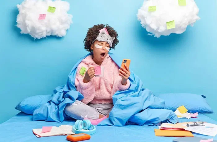 Mavi renkli duvar ve yatakta esneyen bir kadın