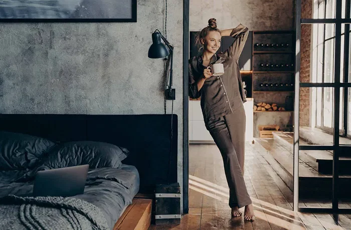 Elinde kahve kupasıyla yatak odasında duran bir kedi