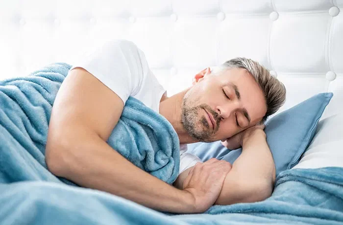 Yan uyku pozisyonunda bir elini başının altına alan bir adam