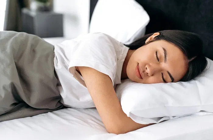 Bir elini yastığın altına koymuş uyuyan bir kadın