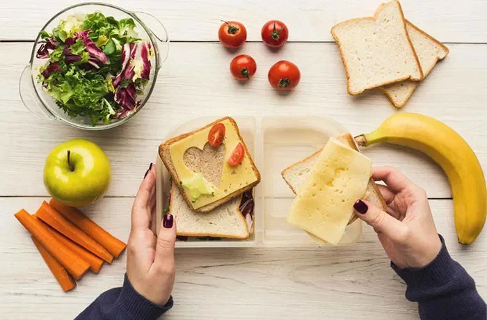 Bir kaba sandviç hazırlayan biri