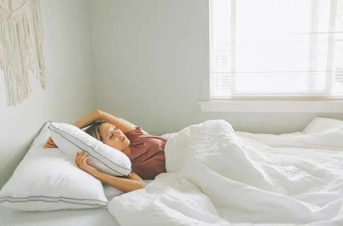 Kollarını arkaya uzatmış uyuyan bir kadın