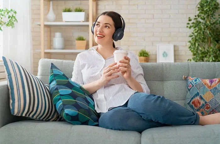 Elinde kahve bardağı tutan kulaklıklı bir kadın