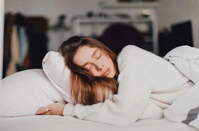 Yastığına sarılmış yan yatan bir kadın